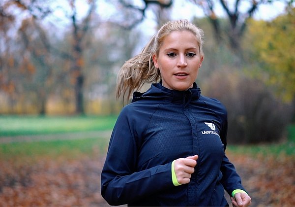 Lauftraining Laufanfänger janina Das Bild zeigt eine Läuferin, die im Wald joggt und als Laufanfängerin mit dem Training beginnt.